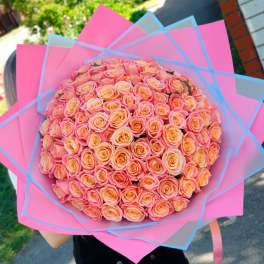Large bouquet of peach and pink roses wrapped in bright pink paper