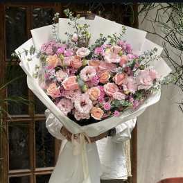 Large bouquet of pink roses and lisianthus wrapped in white paper