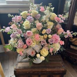 Pastel rose bouquet in a white vase with a sheer ribbon