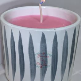 Pink candle in a white ceramic holder with a lit wick