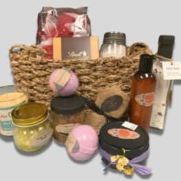 Basket of bath and body gift items with jars, bottles, and bath bombs