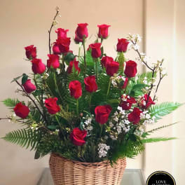 Basket arrangement of tall red roses with white filler flowers and ferns.