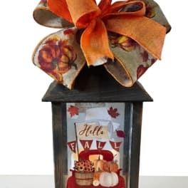 Fall lantern with an orange ribbon bow and autumn-themed insert