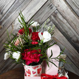 Red and white carnations in a heart-patterned cup with a gift box and ribbon