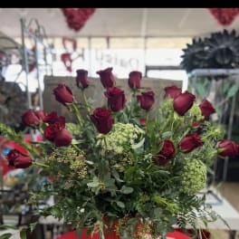 Red roses arranged in a red vase with greenery