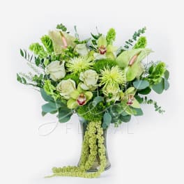 Green and white floral arrangement in a glass vase with orchids and roses