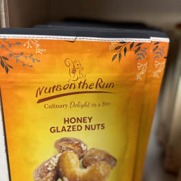Box of honey glazed nuts with a yellow-orange label