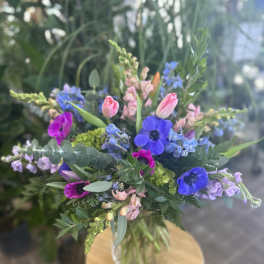Mixed bouquet with blue and pink flowers in a clear vase