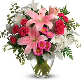 Pink lilies and roses in a clear glass vase with white flowers