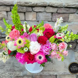 Low white vase filled with pink roses, peonies, anemones and mixed blooms on stone steps