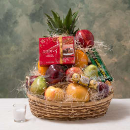 Fruit basket with chocolates and a candle in a woven basket