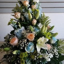 Tall floral spray with white lilies, pastel roses, and blue accents