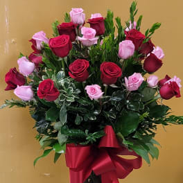 Bouquet of red and pink roses in a clear glass vase with a red ribbon