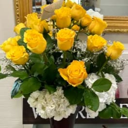 Yellow roses and white hydrangeas in a tall vase