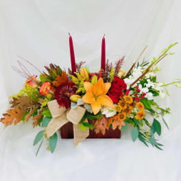 Autumn floral centerpiece with lilies, roses, and candles in a wooden box