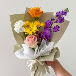 Handheld bouquet with orange, pink, white, yellow, and purple flowers