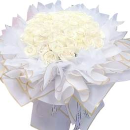 Bouquet of white roses wrapped in white paper with gold trim