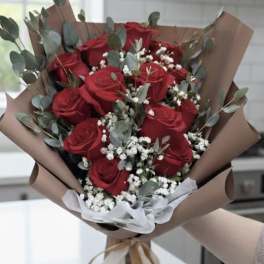 Bouquet of red roses with white filler flowers and eucalyptus in brown paper