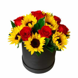Red roses and yellow sunflowers arranged in a black round box