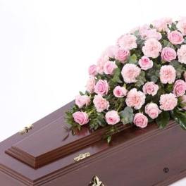 Pink roses and carnations arranged on a brown casket