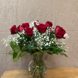 Red roses with baby's breath in a clear glass vase
