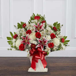 Large red and white floral arrangement with lilies and roses in a white container