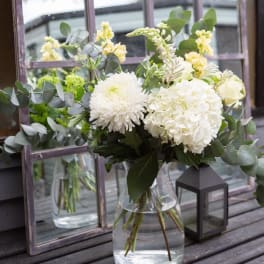 White flowers in a clear glass vase with eucalyptus