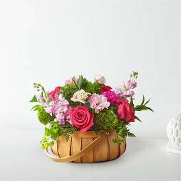 Pink and red flower arrangement in a woven basket