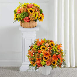 Two autumn floral arrangements with sunflowers and orange roses in white and tan containers.