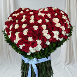 Heart-shaped bouquet of red and white roses tied with a blue ribbon