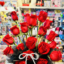 Bouquet of red roses with black wrapping and a white beaded bow in a vase