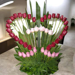Fan-shaped bouquet of pink and red roses with tall greenery