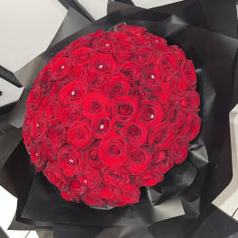 Round bouquet of red roses wrapped in black paper