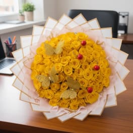 Bouquet of yellow roses wrapped in white paper with gold trim