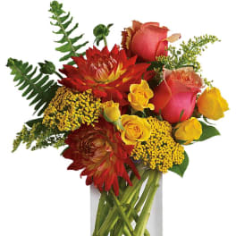 Red and yellow mixed flower arrangement with roses in a clear glass cylinder vase