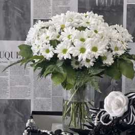 White daisy bouquet in a clear glass vase with green centers