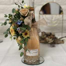 Floral arrangement attached to a wine bottle with a ribbon