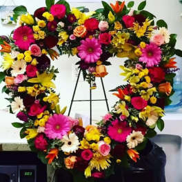Heart-shaped floral wreath with bright mixed flowers on a stand