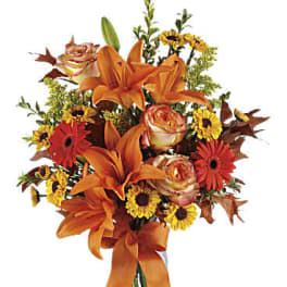Orange lilies and mixed flowers in a clear glass vase