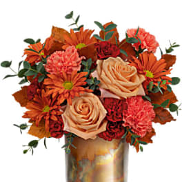 Orange and peach flowers arranged in a metallic vase