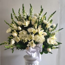 White floral arrangement with lilies, roses, and chrysanthemums in a pedestal vase