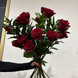 Handheld bouquet of red roses with greenery