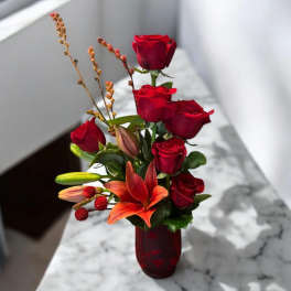 Red roses and orange lilies in a red glass vase