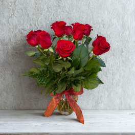 Bouquet of red roses in a glass vase with a red ribbon