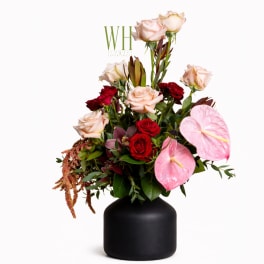 Mixed roses and pink anthuriums in a black vase