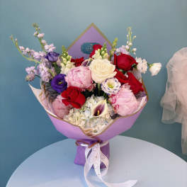 Bouquet of red, pink, white, and purple flowers wrapped in lavender paper