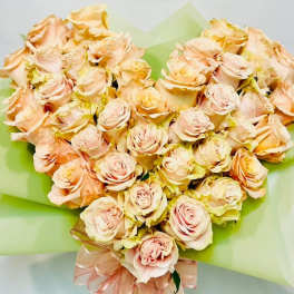 Heart-shaped bouquet of pale peach roses wrapped in green paper