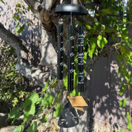 Black memorial wind chime hanging from a tree branch
