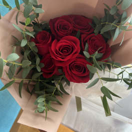 Bouquet of red roses wrapped in blush paper with eucalyptus