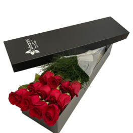Box of red roses with greenery in a black gift box